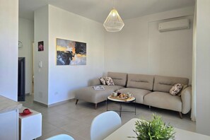 Ein modernes Wohnzimmer mit einer Couch, einem Couchtisch, einer Pendelleuchte und einem Bild an der Wand.