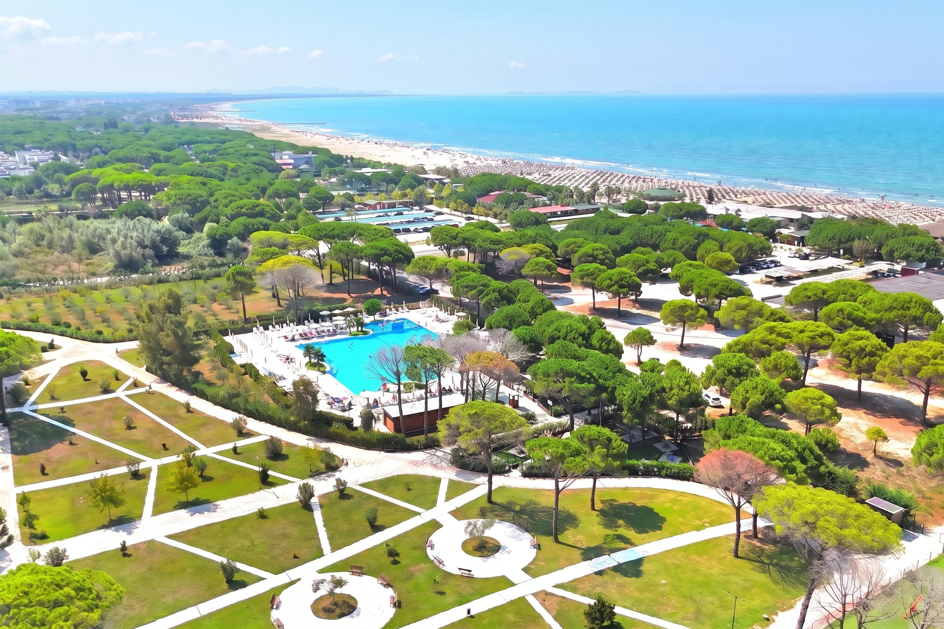 A resort with a central swimming pool, surrounded by landscaped gardens and a beachfront.