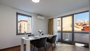 A modern dining area with a white table, black chairs, and a city view through large windows. - Luxury City Penthouse Adialuxe S7, Rijeka, Croatia (Rijeka)