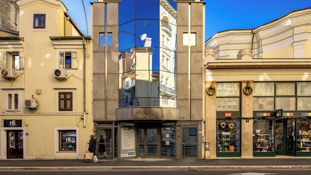 A corner building with a mirrored facade, a storefront with holiday decorations, and a pedestrian crossing the street. - Luxury City Penthouse Adialuxe S7, Rijeka, Croatia (Rijeka)