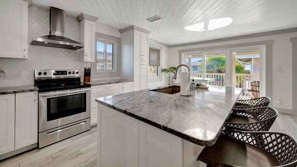 Cocina moderna con armarios blancos, electrodomésticos de acero inoxidable y una isla grande con encimera de mármol.