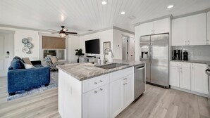 Una cocina moderna con armarios blancos, un refrigerador de acero inoxidable y una isla integrada con fregadero.