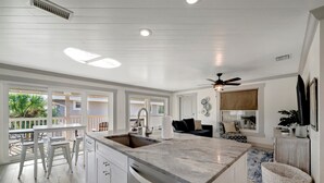 Una cocina moderna con una isla grande, armarios blancos y vistas al exterior.