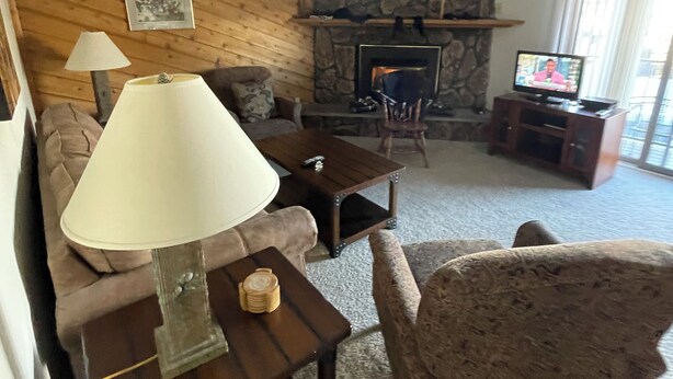 Ein Wohnzimmer mit Kamin aus Stein, einer Couch, einem Couchtisch und einem Fernseher.