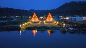 Two triangular wooden cabins with a pond in front, surrounded by a forested area. - The Dewi Tasik Kintamani - Cabin and Villa (Kintamani)