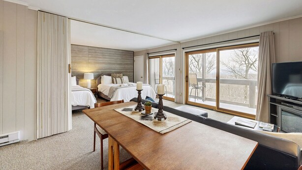 Ett hotellrum med en stor säng, en TV, ett matbord och utsikt över omgivningarna.