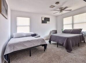 A room with two beds, a ceiling fan, and large windows. - Central midland Sandras house (Midland)