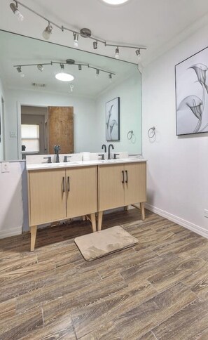A modern bathroom with a large mirror, two sinks, wooden cabinets, and a wooden floor. - Central midland Sandras house (Midland)