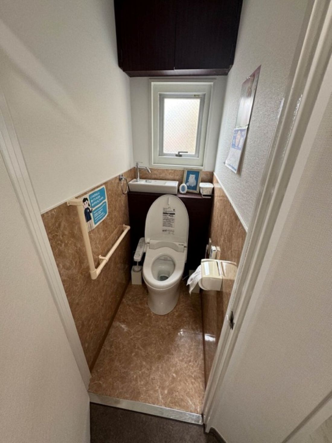 A small bathroom with a toilet, sink, and window.