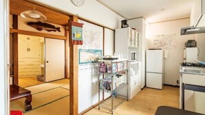 A compact kitchen with a refrigerator, microwave, and stove. A small dining area with a table and chair is visible. - High-quality Japanese modern private accommodation! Experience staying in a shopping district! Japanese/Western style room & bed! Good access to Disney! Free parking! (Shimoshinozakimachi, Edogawa City)