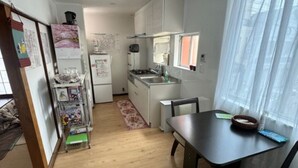 A compact kitchen with white cabinets, a dining table with chairs, and a small window with sheer curtains. - High-quality Japanese modern private accommodation! Experience staying in a shopping district! Japanese/Western style room & bed! Good access to Disney! Free parking! (Shimoshinozakimachi, Edogawa City)