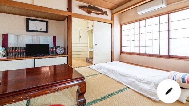 A traditional Japanese room with tatami flooring, a low wooden table, a bed with a white mattress, a television, and a sliding door leading to another room. - High-quality Japanese modern private accommodation! Experience staying in a shopping district! Japanese/Western style room & bed! Good access to Disney! Free parking! (Shimoshinozakimachi, Edogawa City)