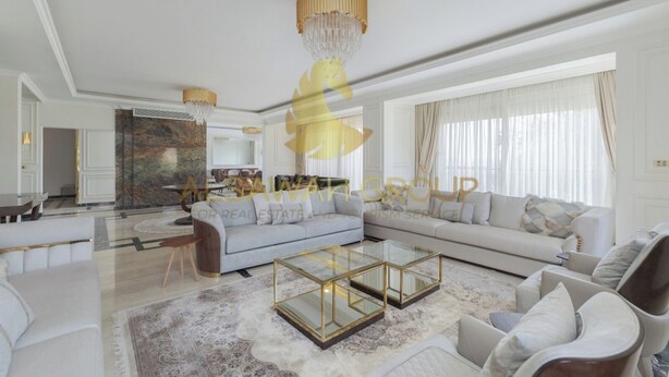 Ein geräumiges Wohnzimmer mit einem großen Ecksofa, einem Glastisch und einer Kronleuchter.