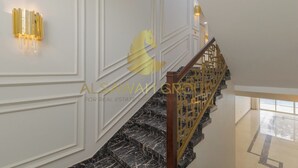 Eine Treppe mit Marmorstufen, weißem Wandverkleidung und einem goldenen Geländer.