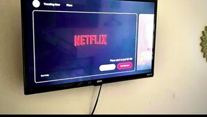 A flat-screen TV mounted on a wall displaying the Netflix interface.