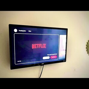 A flat-screen TV mounted on a wall displaying the Netflix interface.