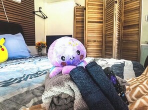 Ein Bett mit einem Kuscheltier, einer Fernbedienung und gefalteten Handtüchern.