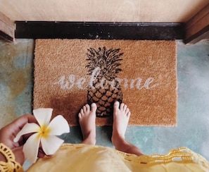 A doormat with a pineapple design and the word "Welcome" on a brown mat.