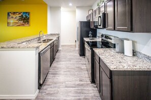 A modern kitchen with granite countertops, stainless steel appliances, and dark wood cabinets.