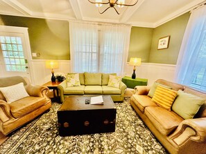 A living room with a green sofa, two armchairs, a coffee table, and a patterned rug.