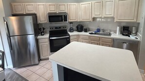 Eine moderne Küche mit einem Edelstahl-Kühlschrank, einer Mikrowelle, einem Backofen und einem Geschirrspüler.