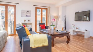 A spacious living room with a sofa, a coffee table, and a TV mounted on the wall.