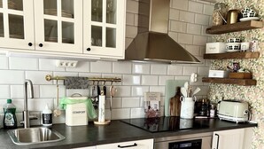 Una cocina moderna con armarios blancos, una campana extractora de acero inoxidable, horno empotrado y encimera de madera.