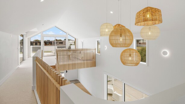 A modern interior with a staircase leading to a balcony, white walls, and hanging wicker light fixtures. - The White Nest by Ready Set Stay (San Remo)