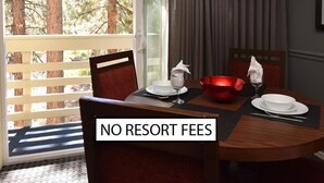 A dining area with a table set for two, a red bowl, white plates, and a wine glass. A sign reads "NO RESORT FEES." - 2 bd suite/6p in Cozy Boutique Lodge between the slopes and Lake Tahoe near all (South Lake Tahoe)