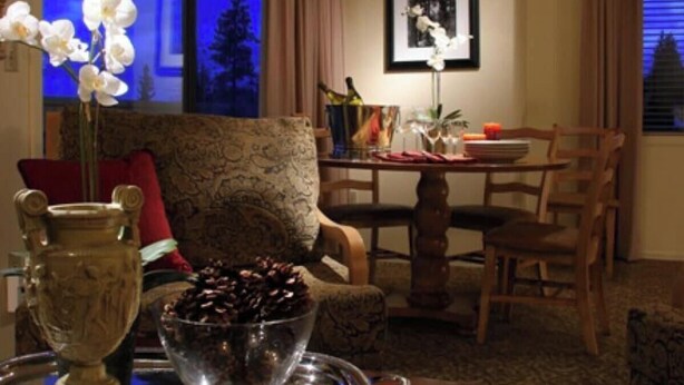 A dining area with a table set for two, a vase of white orchids, and a framed picture on the wall. - 2 bd suite/6p in Cozy Boutique Lodge between the slopes and Lake Tahoe near all (South Lake Tahoe)