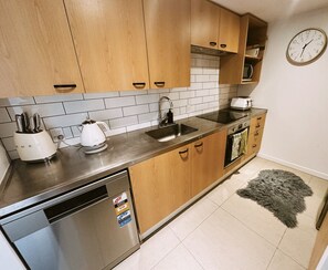 A modern kitchen with wooden cabinets, a stainless steel sink, and a dishwasher. - Chic City Oasis by Stadium & Cathedral (Christchurch)
