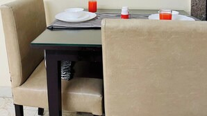 A dining table with two chairs, a glass of red drink, a bottle, and a plate. - Jolo Hotel Gurgaon and Birthday Venues (Gurugram)