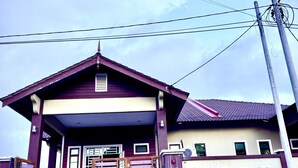 A two-story house with a red and beige exterior, a covered porch, and a gated entrance. - Homestay Selesa KBK Guesthouse (Kuala Terengganu)