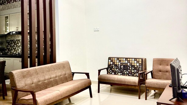 A modern living room with a sofa, two armchairs, a coffee table, and a ceiling fan. - Homestay Selesa KBK Guesthouse (Kuala Terengganu)