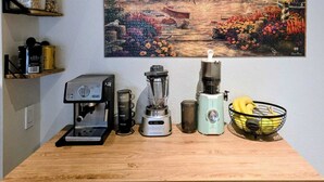 A kitchen counter with a coffee maker, blender, and a basket of bananas.