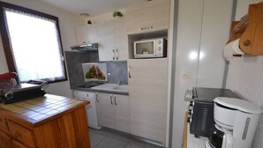 Een kleine keuken met een magnetron, koffiezetapparaat en een klein spoelgedeelte.