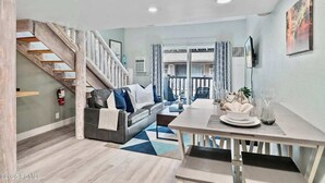 Una sala de estar moderna con una escalera, un comedor y vistas al balcón exterior.