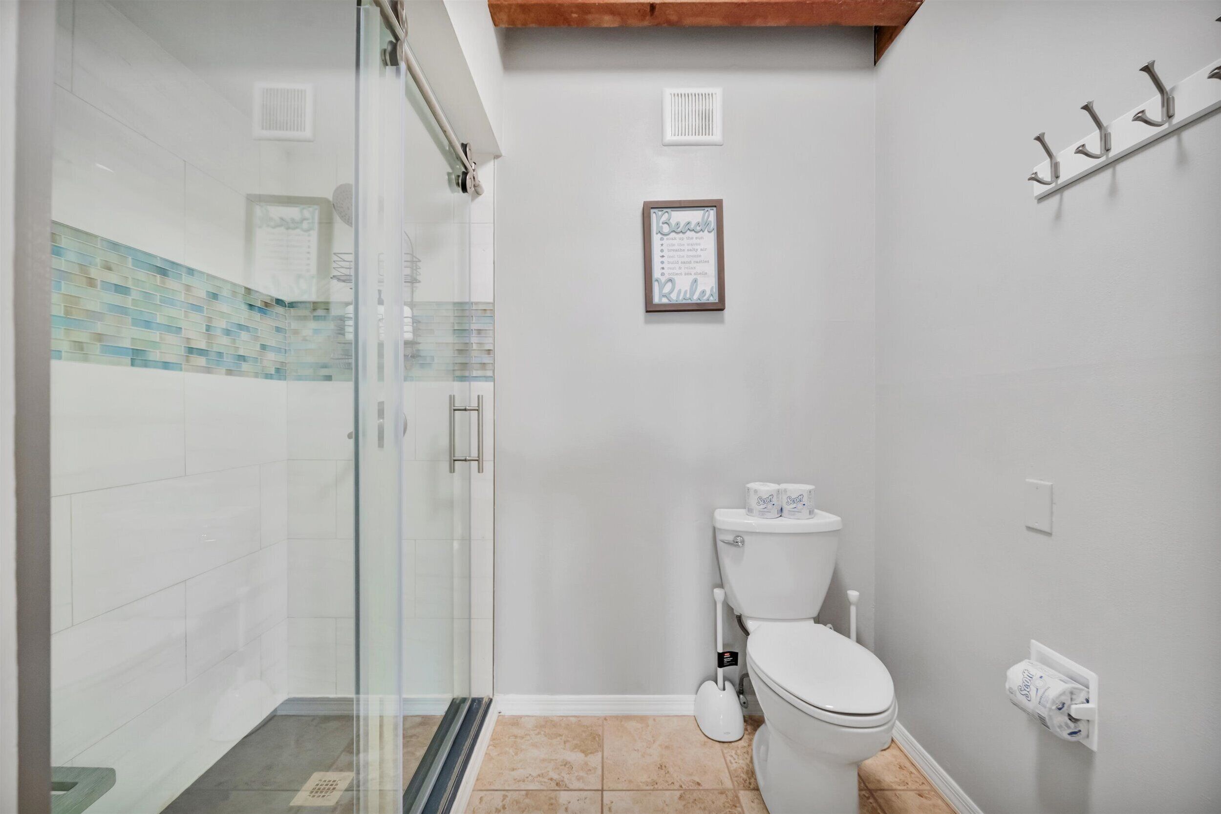 A bathroom with a glass shower enclosure, a toilet, and a wall-mounted towel rack.