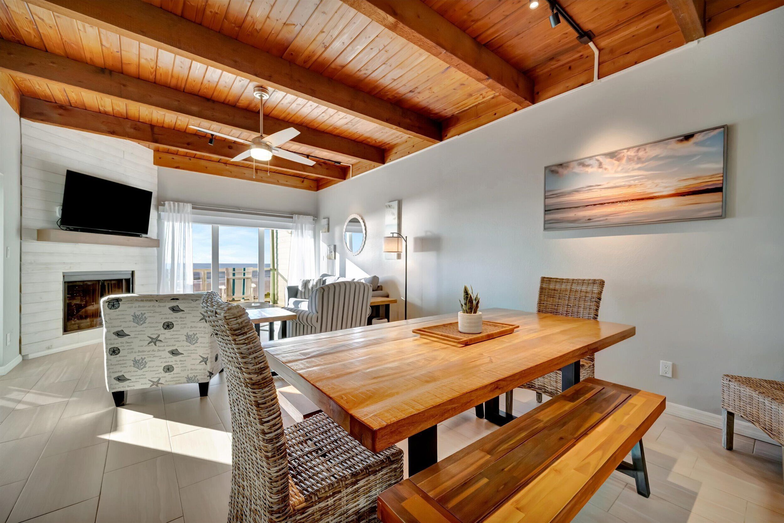 A spacious dining area with a wooden table and benches, surrounded by wicker chairs.