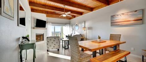 Comedor con mesa de madera y sillas de mimbre, ventilador de techo y ventana grande.