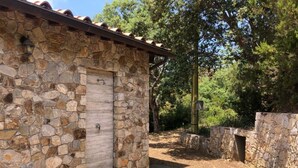 Ein Steinhaus mit einem Ziegeldach, einer Tür und einer Steinsäule mit einer kleinen Öffnung.