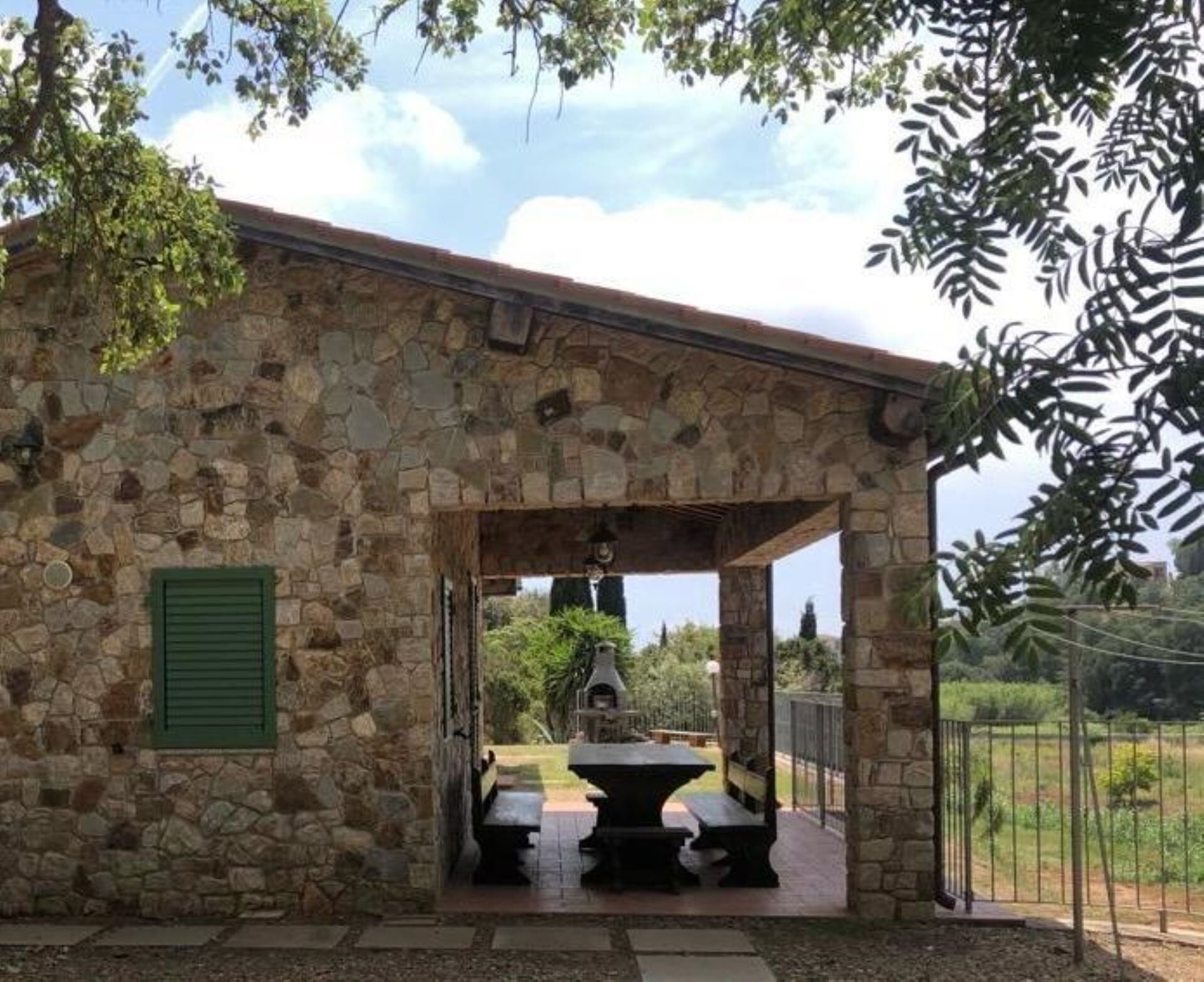 A stone building with a covered outdoor area featuring a stone bench and a grill.
