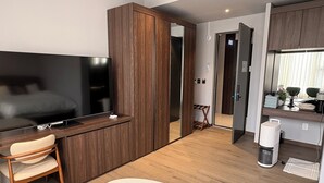 A modern hotel room with a large flat-screen TV, wooden furniture, a small desk, and a compact kitchenette. - laforet space (Gongju)