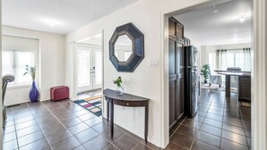 A spacious living area with a dark wooden floor, a red ottoman, a blue vase, and a hexagonal mirror on the wall. - 4 Tvs, King Bed, Across Recreational Park, Tennis Court, Near Commercial Center (Ajax)