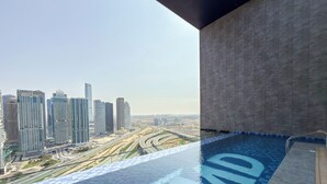 A rooftop pool with a city view, modern architecture, and a clear sky. - Modern Apartment with Rooftop Amenities (Dubai)
