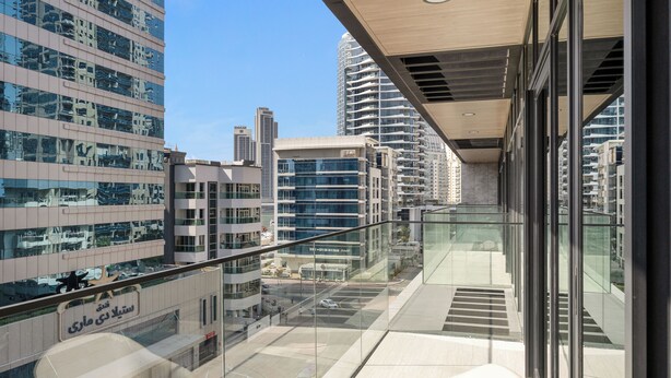 A modern building with a glass balcony, large windows, and a view of the cityscape. - Modern Apartment with Rooftop Amenities (Dubai)