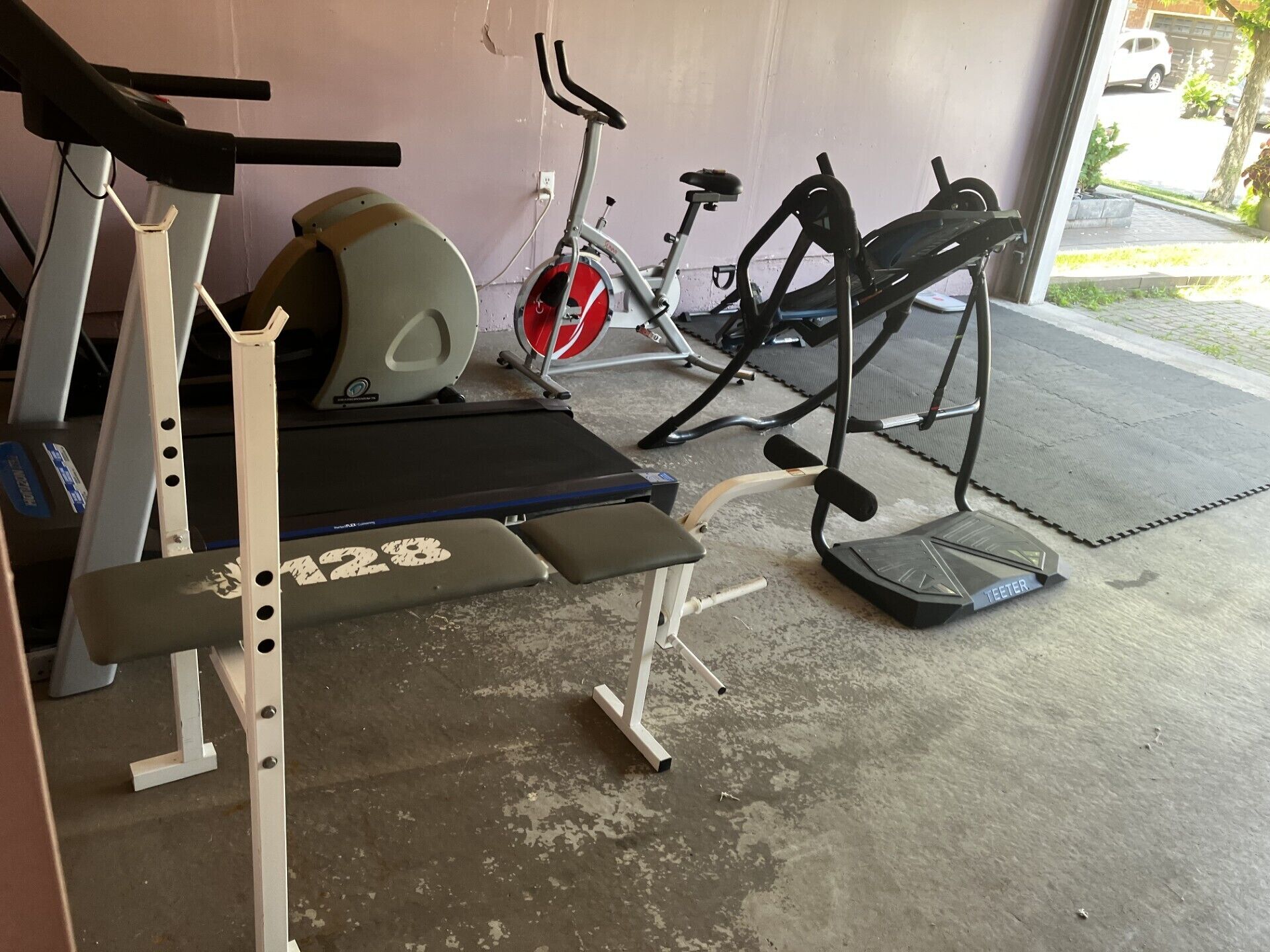 Una palestra con una panca, un tapis roulant e una cyclette.