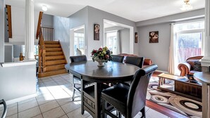 Un amplio salón con una mesa de comedor, un sofá y una escalera.