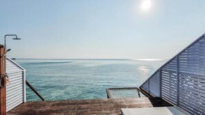 A view from a balcony overlooking a calm sea, with a metal railing and a wooden deck. - Arasatu Villas and Sanctuary (Maratua Island)