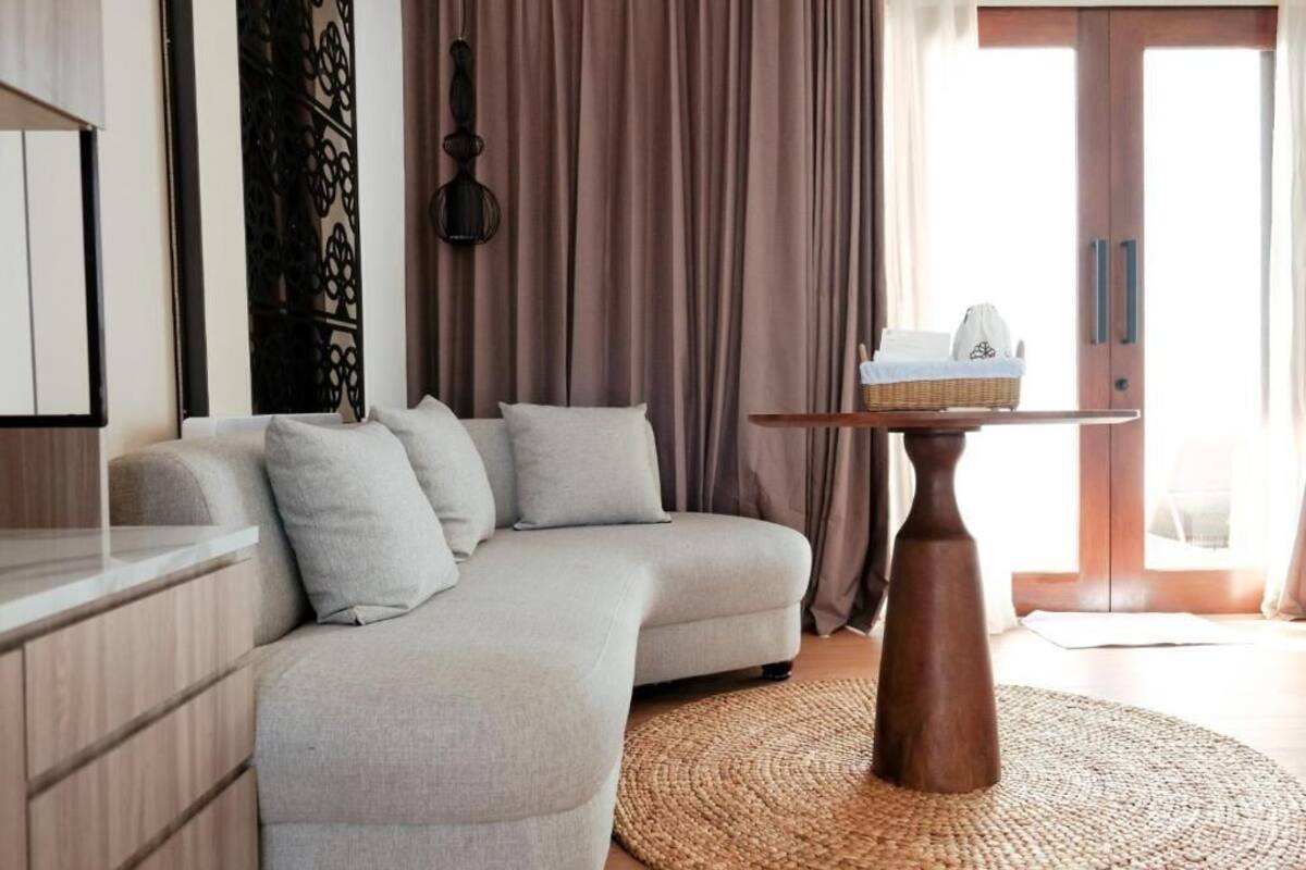 Una sala de estar moderna con un sofá de color claro, una mesa de centro de madera y un tapete tejido.
